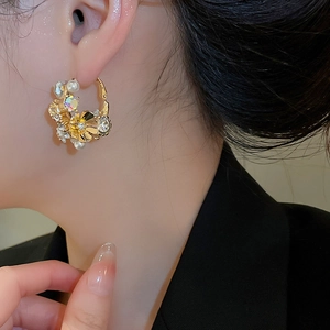 Detail view of gold flower earrings with pearls and crystals on female model