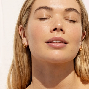 Close-up of model wearing 18K gold-plated irregular twisted double hoop earrings