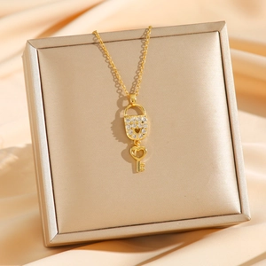 Collier élégant doré avec pendentif serrure et clé en zircons sur fond de soie champagne