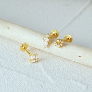 Detailed close-up of gold s925 silver ear studs with teardrop and square gemstones