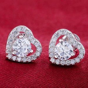 Macro view of heart-shaped silver earrings with clear cubic zirconia and halo diamond setting