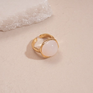 Detail of a gold adjustable ring featuring a large round translucent pink gemstone inlay
