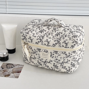 Close-up of floral quilted toiletry bag with zipper ribbon detail and ribbon handle