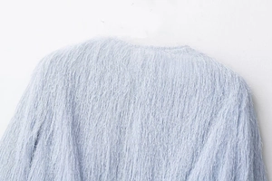 Detail shot of light blue fringe jacket showing soft plush texture and collar stitching