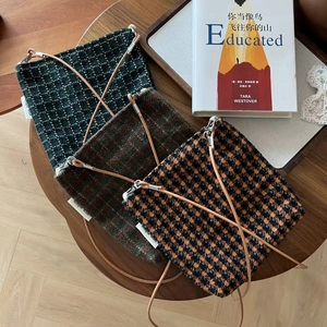 Three retro plaid tweed mini crossbody phone bags in green, brown, and orange on a wooden table