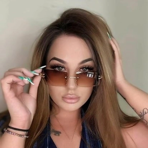 Detail of square rimless sunglasses with brown gradient lenses and gold-tone metal hinges