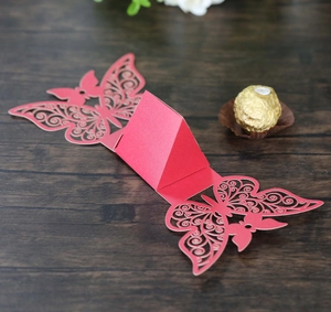 Detailed laser-cut butterfly wedding favor box in red paper with a chocolate reference