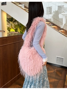 Detailed view of pink faux fur shoulder bag with long tassel texture on a model