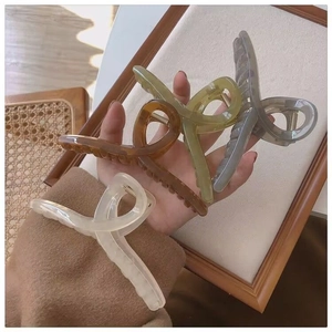 Close-up of four matte claw clips in cream, amber, green, and grey on a wooden background