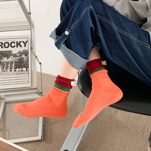 Close-up of orange ribbed skateboard socks with red stripes and white SA label