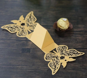 Macro view of golden laser-cut butterfly candy box with hollow wings for wedding party
