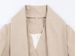 Detail of the oversized beige blazer lapel featuring a smooth white satin lining