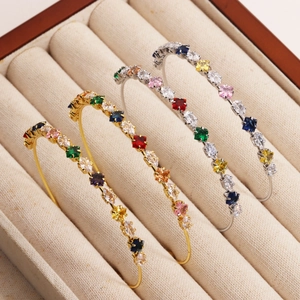 Three-piece gold and silver plated open bangles with colorful zircon gemstones in a display case