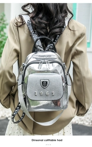Detail view of silver metallic backpack featuring 1961 metal logo and studded shoulder strap
