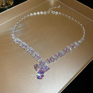 Close-up of V-shaped silver necklace with pink teardrop zircon and square crystals