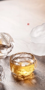 Detailed close-up of amber hammer pattern glass teacup on a rustic wooden tea table