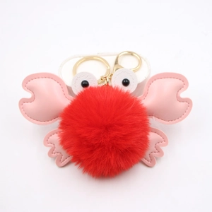 Close-up of a plush crab keychain with red fur ball, pink PU leather claws and golden hook