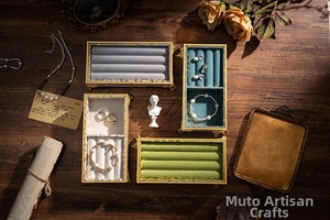 Macro view of vintage gold jewelry tray featuring colorful velvet lining and ornate relief