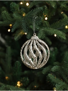 Macro view of champagne gold glittery hollow spiral Christmas ball hanging on a tree