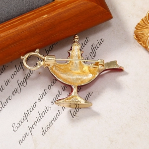 Back view of vintage golden Aladdin lamp brooch showing pin clasp and metallic texture