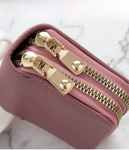 Detalle de la cartera de cuero rosa con cremalleras dobles de metal dorado de alta calidad