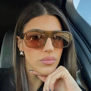 Detail of amber oversized square sunglasses with brown gradient lenses on model