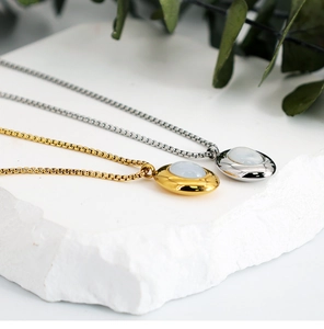 Detailed close-up of oval shell pendants in gold and silver finish on textured stone