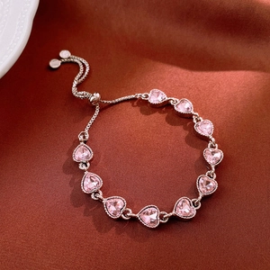 Detailed top view of pink heart zircon bracelet with adjustable slider on silk fabric