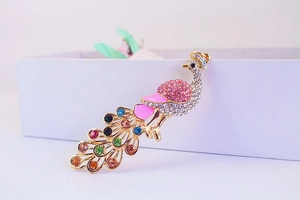 Close-up of golden peacock brooch with colorful rhinestones and pink enamel details