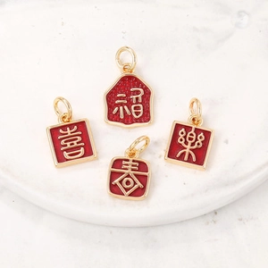 Détails de quatre breloques dorées en émail rouge avec caractères chinois gravés