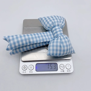 Detailed top view of a blue plaid fabric bow charm weighing 15.3g on a digital scale