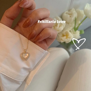 Detail of heart pendant necklace with white mother of pearl and pavé crystals on gold chain