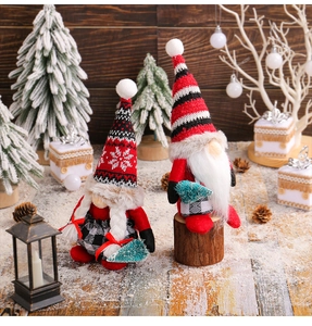 Close-up of two Christmas gnomes with knit hats on snowy wood surface for decor