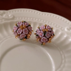 Macro view of pink ceramic flower cluster earrings with crystals on a white plate