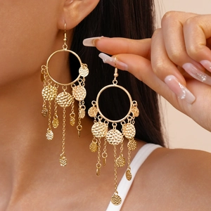 Détail de boucles d'oreilles bohèmes dorées avec paillettes martelées sur un mannequin