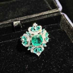 Luxurious square-cut green emerald ring with micro-pave diamonds in a black velvet box