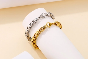Detail of gold and silver Byzantine chain bracelets with lobster clasp on white pillar
