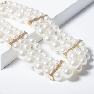 Close-up of triple-layered pearl necklace with textured gold hammered metal links