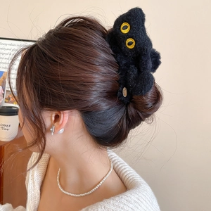 Détail d'une pince à cheveux chat en peluche noire portée par une femme dans un cadre doux