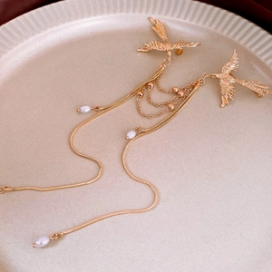 Detail of phoenix brooch with pearl tassels and golden metal chain on a ceramic tray