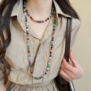 Close-up of colorful faceted crystal beaded necklaces layered on a white linen shirt