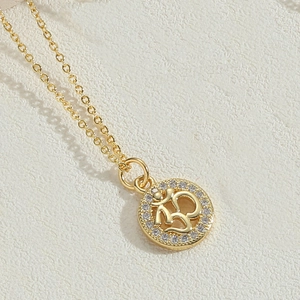 Detailed view of a gold Om symbol pendant with sparkling zircon bezel on leather