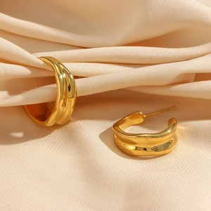 Detailed macro view of 18K gold plated irregular C-shape earrings on beige silk fabric