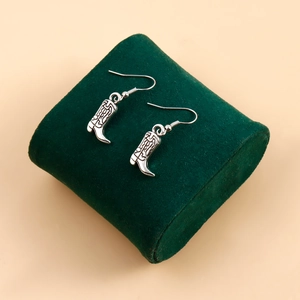 Gros plan de boucles d'oreilles bottes de cowboy argentées avec motifs vintage
