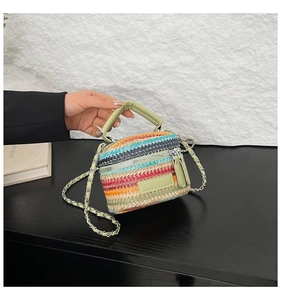 Dettaglio della borsa a secchiello intrecciata a righe colorate con manico in pelle