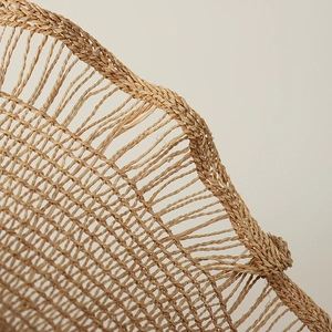 Detailed close-up of woven raffia texture and wavy edge on a wide brim sun hat
