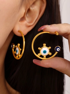 Detail view of gold enamel evil eye hoop earrings on a model showing bohemia style