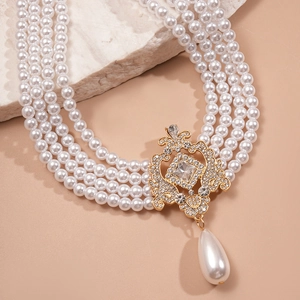 Detail of baroque multi-layer pearl necklace with ornate golden rhinestone pendant