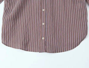 Detail of red striped cotton shirt featuring curved hem and white button closure