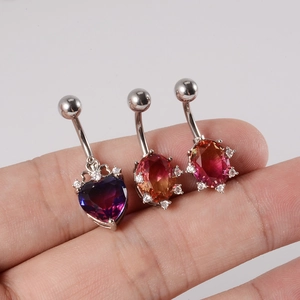 Detailed macro view of heart-shaped purple and oval pink zircon navel rings on a finger